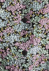 Tecido preto com um padrão floral multicolorido em rosa, verde e amarelo. Apresenta botões pretos ao longo da frente. Textura suave.