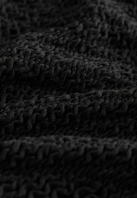 Melnas teksturētas audums ar viļņotu rakstu, cieši austs ar paceltām malām, kas nodrošina mīkstu un sarežģītu izskatu.