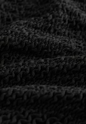 Mustritud must kangas, millel on laineline mustr, tihedalt kootud väljaulatuvate ribadega, pakkudes pehmet ja keerukat välimust.