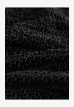 Tessuto nero texturizzato con un motivo ondulato, intrecciato a stretto contatto con rilievi sollevati, che offre un aspetto morbido e intricato.