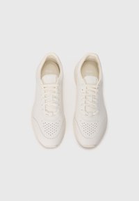 White leather sneakers with perforated design, flat shoelaces, and cream-colored rubber sole. Simple and clean aesthetic. BOSS branding visible.