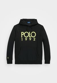 Sudadera negra con capucha, confeccionada en tela suave, con un bolsillo delantero. Texto "POLO 1992" en amarillo reflectante. Pequeño logo en la manga izquierda.