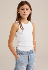 Balti ribuoto audinio tankas užsiliepsnojęs su šviesiai mėlynomis džinsinėmis kargo šortais, turinčiais aukštą liemenį ir priekines kišenes. Modelis stovi su rankomis kišenėse.
