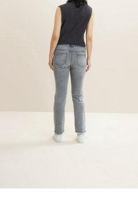 Jeans de mezclilla gris con un diseño de pierna recta, que presentan bolsillos traseros y un ligero desgaste, combinados con una blusa sin mangas negra.