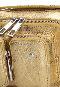 Gouden leren tas met textuur, voorzien van meerdere met rits afsluitbare compartimenten en hardware in zilverkleur. Gladde afwerking met minimale stikseldetails.