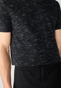 Black V-neck T-shirt with a textured pattern featuring dark and light streaks. Paired with black elastic waistband pants.