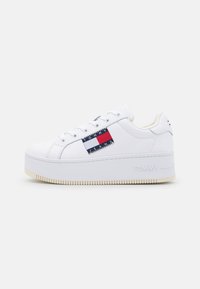 Bílé tenisky s platformní podrážkou, s červeným a modrým logem na boku a jemnými texturovanými akcenty. Hladký kožený materiál.