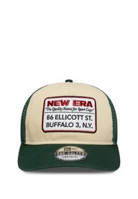 Beige cepure ar zaļu vizieri, kurā ir balts izšūts uzlīme ar tekstu "NEW ERA" un adresi. Snapback dizains, poliestera materiāls.