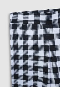 Leggings bianco e nero a scacchi con motivi alternativi solidi e a strisce, realizzati in un tessuto morbido ed elastico.