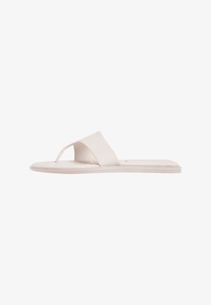 Sandalia plana blanca con una correa ancha y bucle para el dedo, diseño simple y minimalista, aislada sobre fondo blanco.