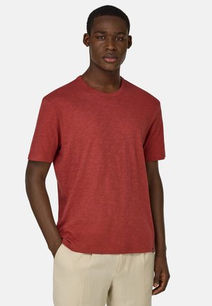 Rotes T-Shirt mit Rundhalsausschnitt aus strukturiertem Stoff, kurzen Ärmeln und lockerer Passform, mit einem kleinen Logo-Detail am Saum.