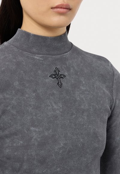 Grå ribbad polotröja med en svart broderad korsdetalj. Tyget har en subtil lyster och en figursydd silhuett.