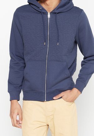 Marine blauwe zip-up hoodie met een gestructureerd bovenpaneel, verstelbare trekkoordkap en een voorzak. Gemaakt van zachte, rekbare stof.