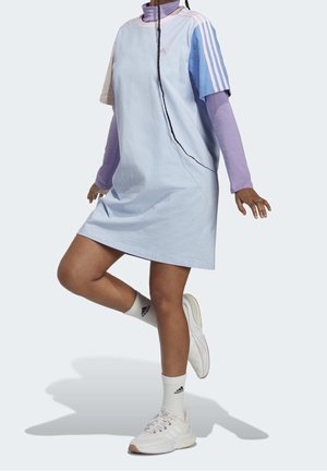 Robe bleu clair à manches courtes, portée sur un haut à manches longues violet. Trois bandes blanches sur les épaules. Baskets blanches et chaussettes.