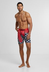 Boxer-briefs rouges et noirs à motif à carreaux, comportant une ceinture étiquetée "PSD" et une texture de tissu lisse.