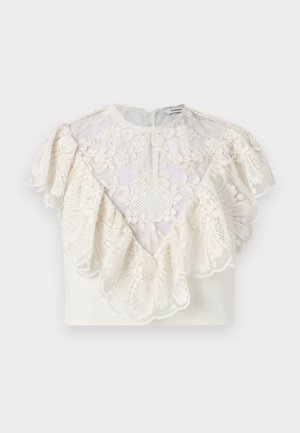 White cropped blouse with intricate floral lace overlay, ruffled edges, and a small back button closure.