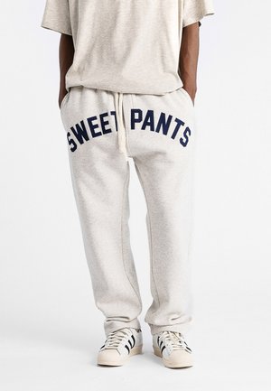 Jogging léger gris avec "SWEET PANTS" imprimé en bleu marine sur l'avant. Comprend une taille à cordon de serrage et un design à jambes fuselées.