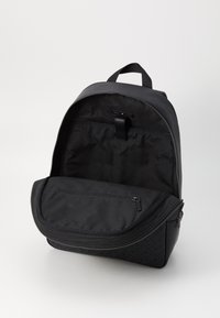 Black backpack made of nylon with a smooth texture, featuring a wide zippered opening, inner pocket, and subtle patterned accents on the base.
