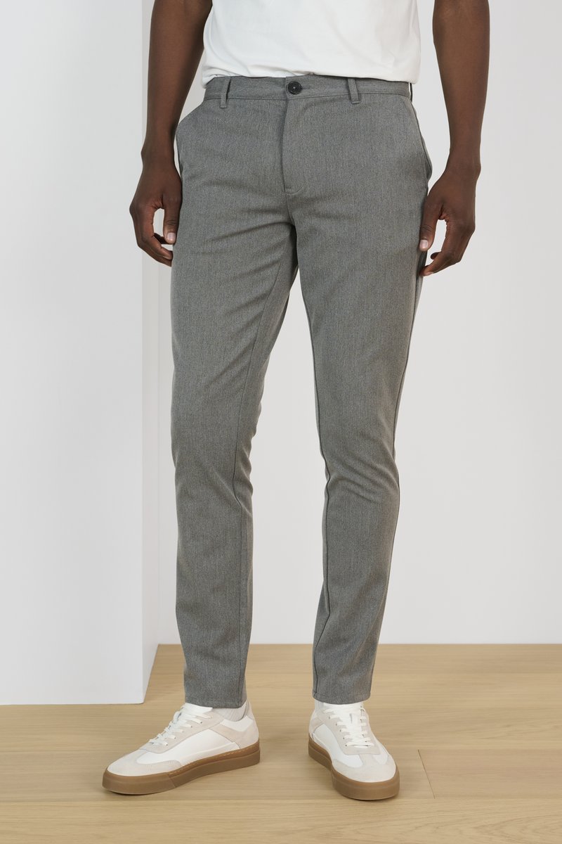 Grijze, gestructureerde broeken hebben een rechte snit en een knoopsluiting. Gecombineerd met witte sneakers met een tan kleurige zool.