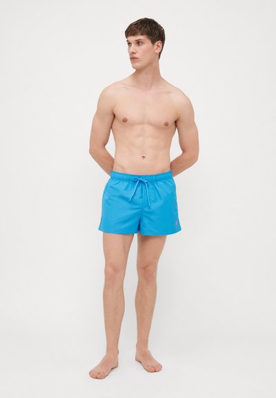 Shorts de bain bleus avec une taille élastique et un cordon de serrage, présentant un petit logo rose à l'avant. Matière lisse et légère.