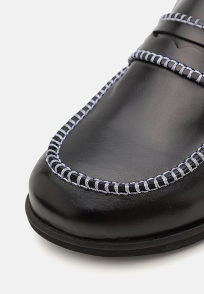 Scarpa in pelle nera dal design elegante, con cuciture grigie a contrasto lungo i bordi e una superficie liscia e lucida.
