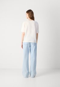Hvit kortermet t-skjorte med rett snitt, kombinert med lyseblå vide jeans, med baklommer og myk denim tekstur.