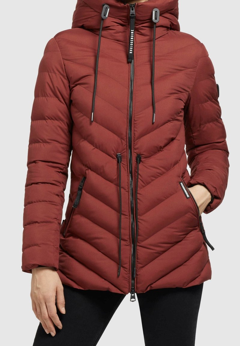 Chaqueta acolchada roja con un diseño de chevron, que cuenta con un cierre de cremallera, capucha ajustable y detalles en negro. Incluye dos bolsillos laterales.