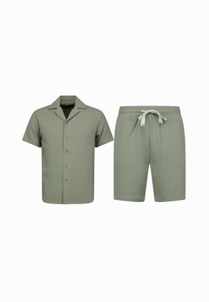 Korte mouw blouse met knopen en korte broek met trekkoord van gestructureerde olijfgroene stof, getoond op een witte achtergrond.