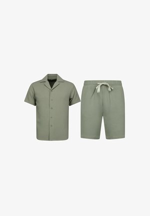 Korte mouw blouse met knopen en korte broek met trekkoord van gestructureerde olijfgroene stof, getoond op een witte achtergrond.