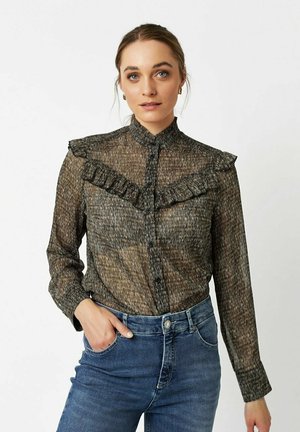 Black and gold patterned blouse with ruffled collar, button front, and long sleeves, paired with blue denim jeans. Soft, textured fabric.