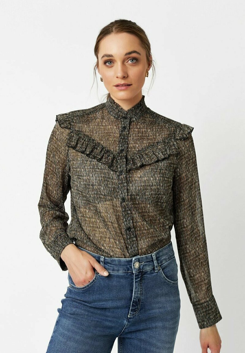 Black and gold patterned blouse with ruffled collar, button front, and long sleeves, paired with blue denim jeans. Soft, textured fabric.