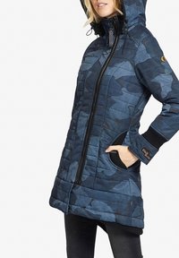 Polstret navy blå jakke med camouflage mønster, lynlåslukning, hætte og sidelommer. Ribbet manchetter og branddetalje på ærmet.