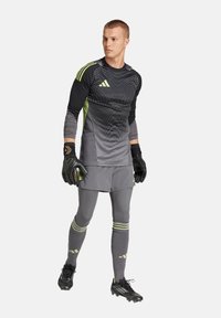 Uniforme de gardien en noir, gris et vert fluo. Comprend des manches longues, un design ajusté et des gants. Inclut des rayures et des motifs texturés.