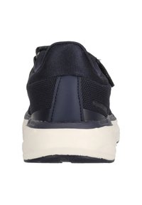 Laivastonsininen tennari, jossa on teksturoitu päällinen, pehmustettu kaulus ja valkoinen pohja. Sisältää tarranauhan, joka helpottaa säätämistä.