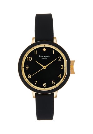Okrągły czarny zegarek z złotymi cyframi, wskazówkami i obwódką, czarnym paskiem oraz logo "kate spade NEW YORK" na tarczy.