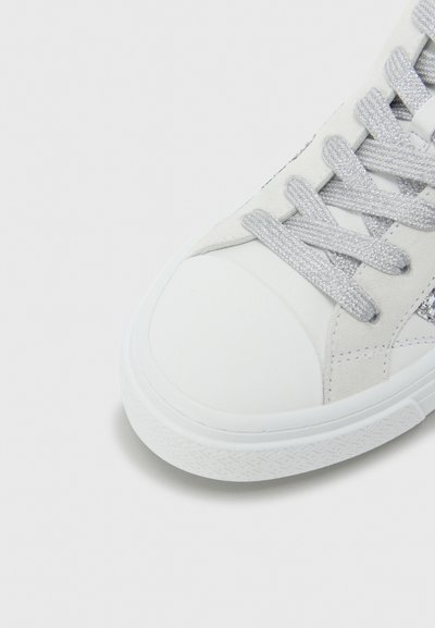 Baskets blanches avec une tige en daim, des lacets gris texturés et une semelle en caoutchouc. Bout arrondi et détails de couture sur le côté.