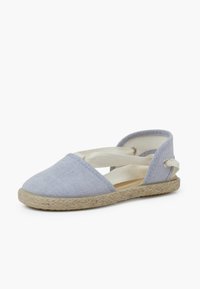 Lichtblauwe espadrille met een canvas bovenkant, kruisende elastische banden en een jute touwzool. Ronde neus en minimalistisch ontwerp.
