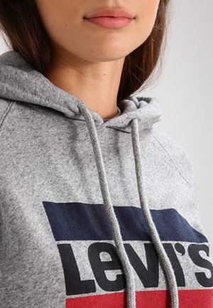 Grå hoodie med dragsko, som har en framträdande Levi's-logotyp. Designen inkluderar blå och röda horisontella ränder över bröstet.