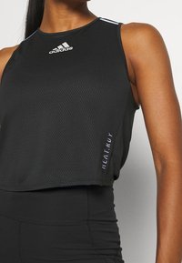 Svart ärmlös sporttopp med en strukturerad mönstring, med vit Adidas-logga och texten "HEAT.RDY" på sidan.