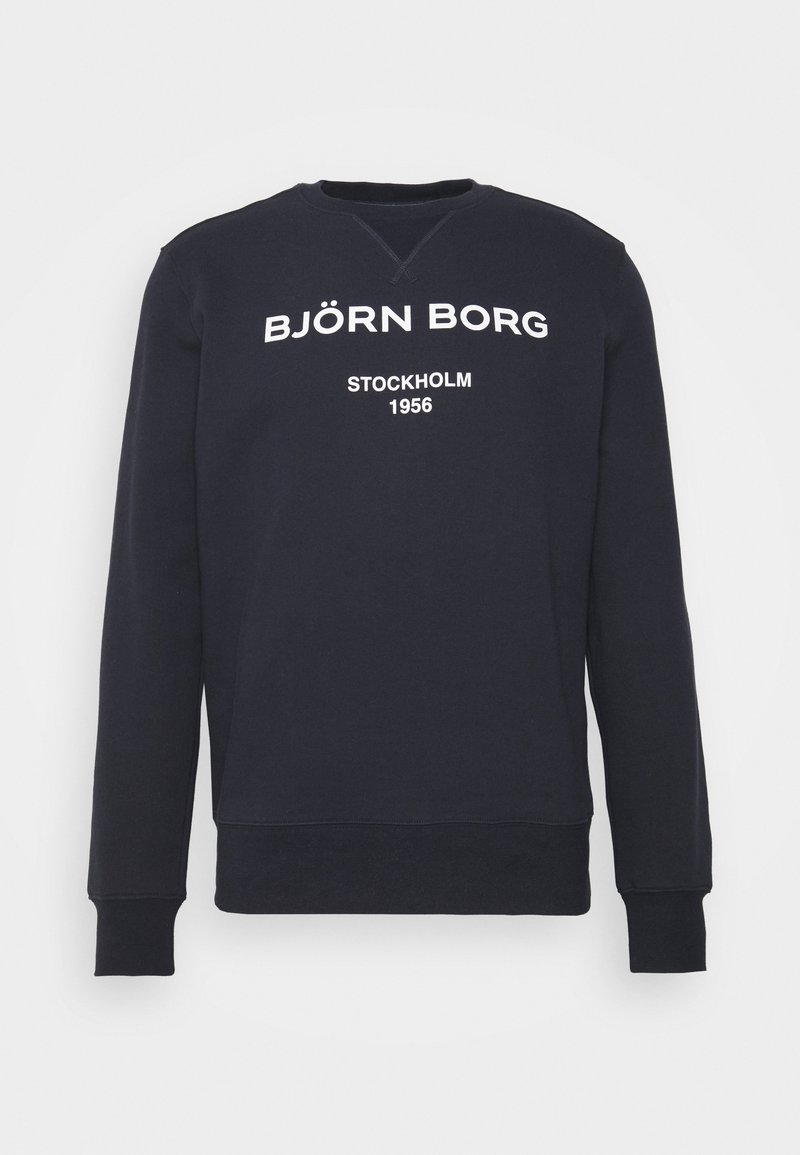 Sweat-shirt bleu marine col rond avec texte blanc "BJÖRN BORG" et "STOCKHOLM 1956" sur la poitrine, manches longues, poignets et bas côtelés.