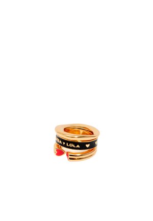 Anillo dorado con banda negra que presenta el texto "Bimba y Lola", un detalle de corazón rojo y pequeños motivos de corazones. Diseño elegante y moderno.
