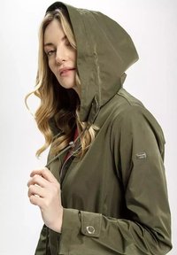 Oliwkowa wodoodporna kurtka z ściąganym kapturem, zamkiem błyskawicznym z przodu oraz zatrzaskami. Posiada subtelną logo na rękawie.