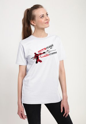 Camiseta blanca de algodón con un gráfico de un personaje rojo y negro y el texto "MARVEL" y "STUDIOS" en rojo sobre un fondo negro.