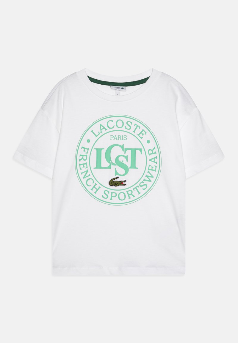 Bílý bavlněný tričko s kulatým zeleným grafikou, která obsahuje nápisy "LACOSTE," "PARIS" a "FRENCH SPORTSWEAR," plus vyšívané logo krokodýla.