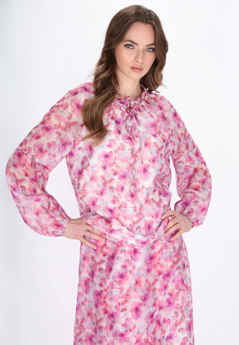 Blusa leggera con motivo floreale nei toni di rosa, viola e bianco. Presenta maniche lunghe, un scollatura arricciata e una vestibilità comoda.