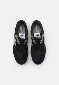 Melni sporta apavi ar sietu un zamša augšdaļu, ar pelēku "N" logo, auklu aizdari un mīkstu iekšējo oderi.