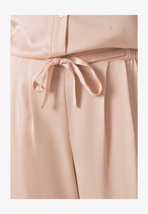Lichtroze bloes met een gladde, zijdeachtige textuur, een gestrikte tailleband en kleine decoratieve versieringen.