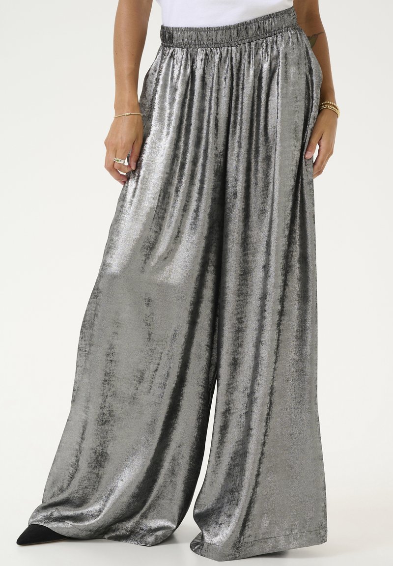 Pantalons larges en argent métallique avec une surface lisse et légèrement texturée. Dotés d'une ceinture élastique pour le confort et d'un design fluide.
