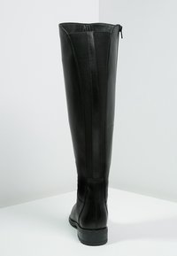 Svart läder knähöga stövlar med en slät yta, utrustad med dragkedja på sidan och elastisk panel för flexibilitet. Stabil gummisula.