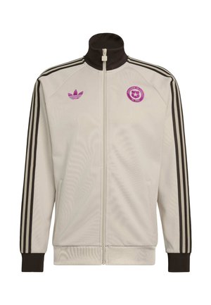 Veste de survêtement Adidas blanche avec fermeture éclair, bandes noires sur les manches, col et poignets noirs, logo Adidas violet et emblème de football du Chili sur la poitrine.